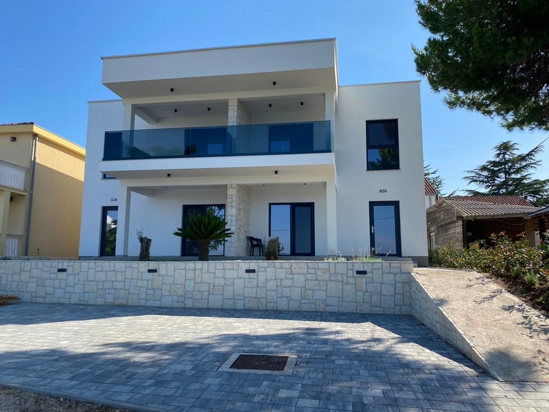 Villa avec balcons en verre bleus au-dessus du mur en pierre naturelle