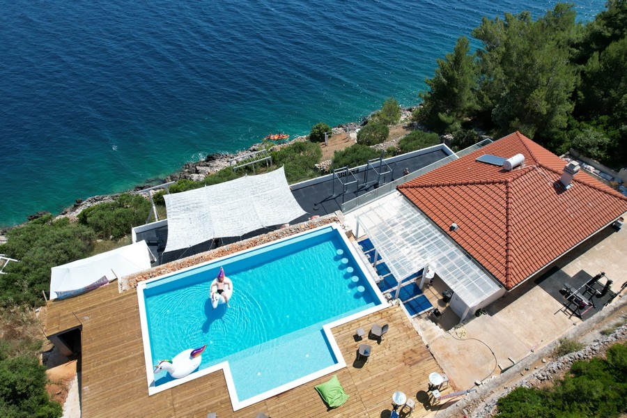 Piscine avec voile d'ombrage et terrasse en bois au-dessus de l'eau