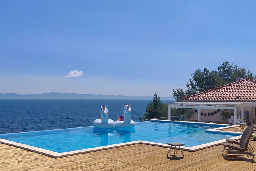 Piscine à débordement avec vue mer et vaste terrasse en bois