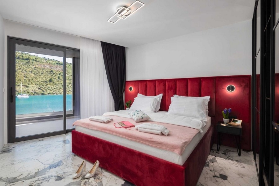 Chambre avec lit capitonné rouge et vue mer