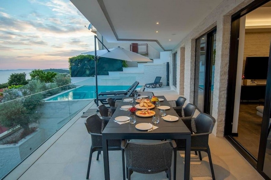 Terrasse avec table à manger, vue mer et piscine à Primosten