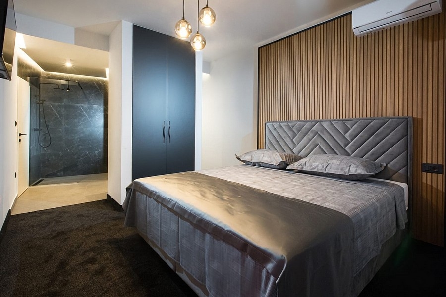 Chambre avec mur lambrissé en bois et salle d'eau intégrée