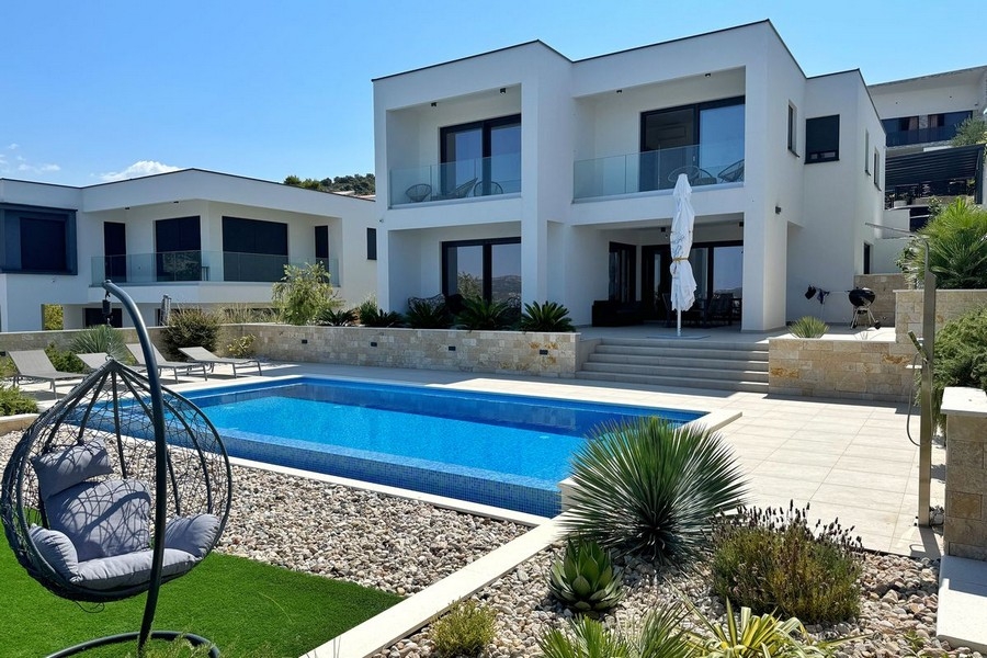 Villa avec piscine et fauteuil suspendu dans le jardin de gravier