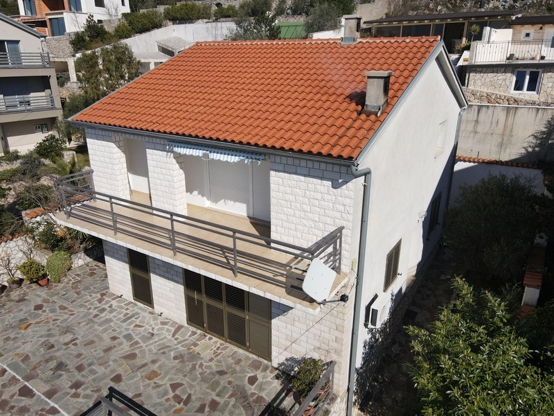 Maison à toit de tuiles et balcon au-dessus de la cour pavée