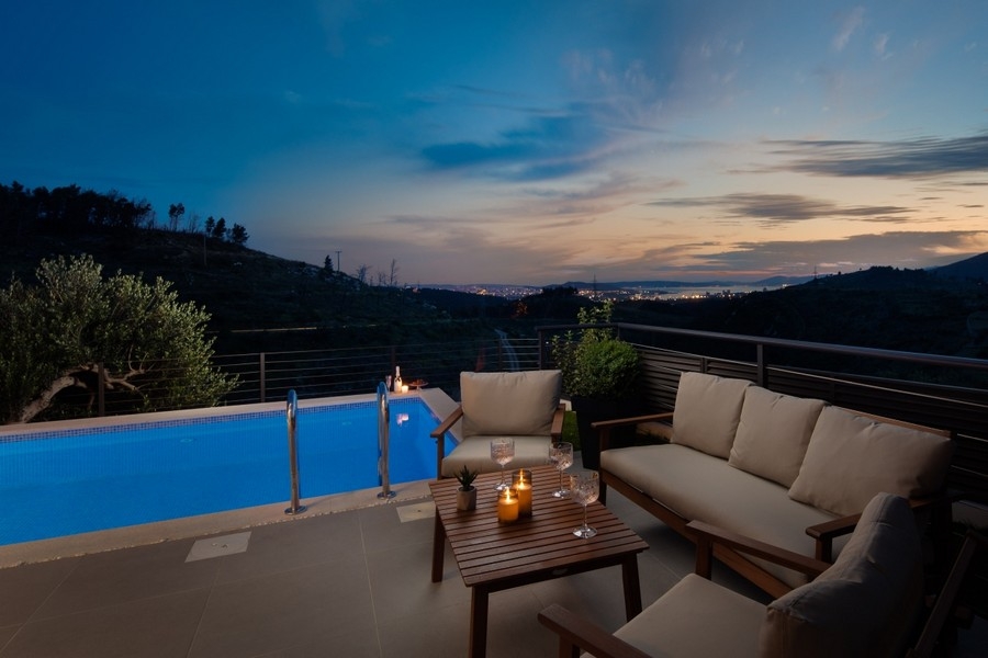 Lounge avec bougies au bord de la piscine devant les lumières de la ville