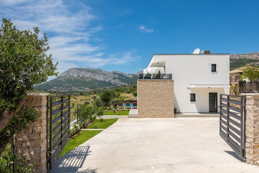 Allée d'accès avec portail menant à la villa, montagnes à l'arrière-plan
