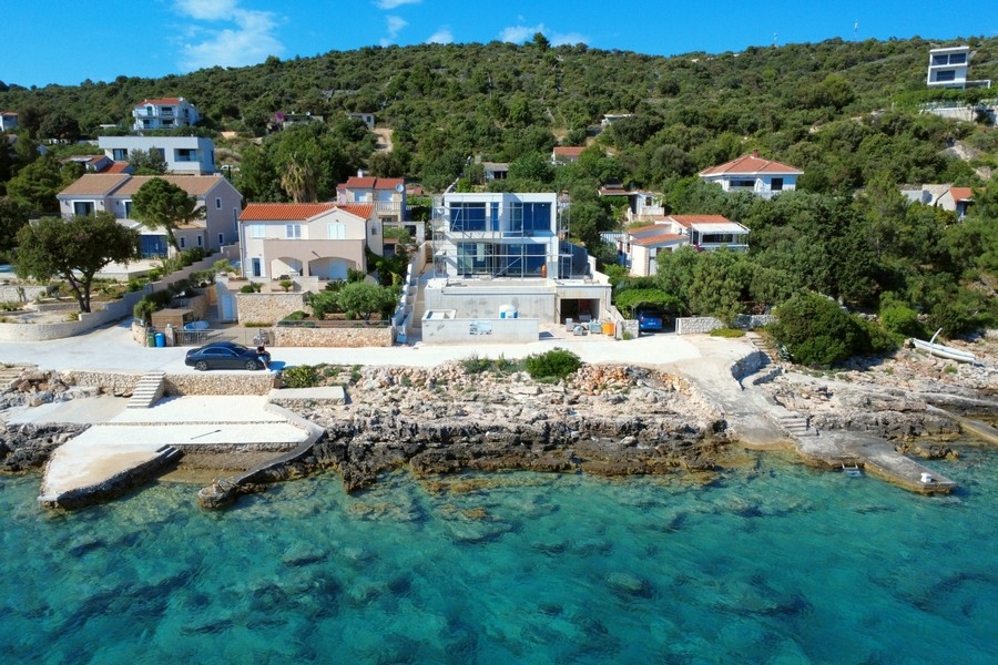 Vue aérienne de la maison de verre sur la rive rocheuse avec eau turquoise