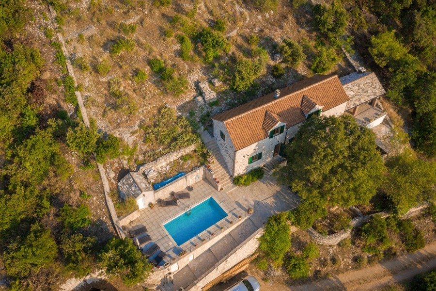 Vue aérienne de la maison en pierre avec piscine sur le versant boisé