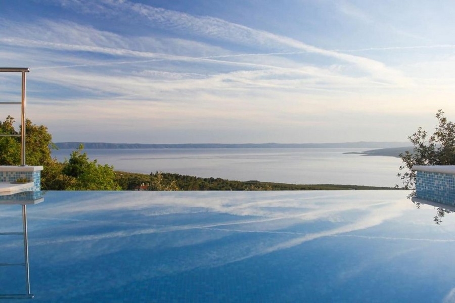 Piscine à débordement à la surface lisse comme un miroir au-dessus de la baie
