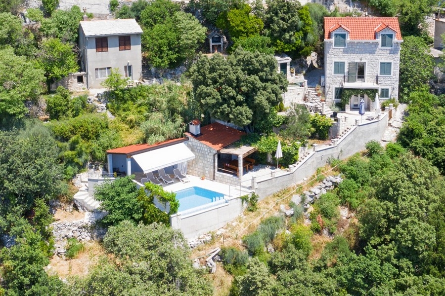 Vue aérienne d'une maison en pierre avec piscine à débordement et vue mer
