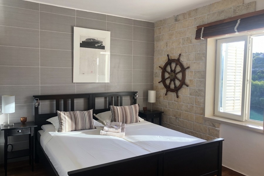 Chambre avec mur en pierre et fenêtre donnant sur la mer