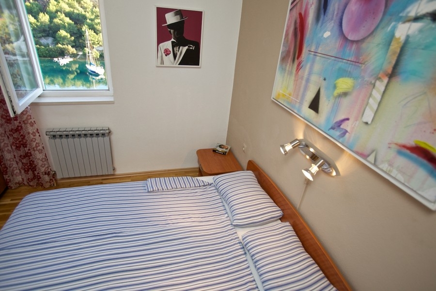 Chambre avec vue par la fenêtre sur la baie et un voilier