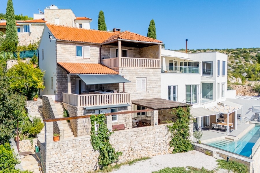 Maison en pierre avec balcons à côté de l'immeuble neuf blanc au bord de la piscine