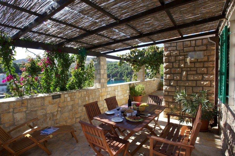 Terrasse couverte en pierre naturelle avec salon de jardin