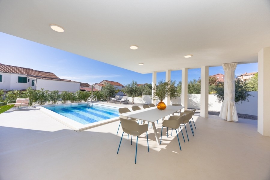 Terrasse couverte avec coin repas et vue sur la piscine
