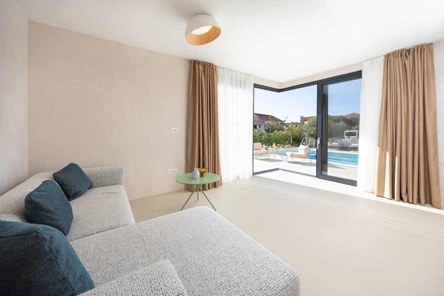 Salon avec canapé et vue sur la terrasse et la piscine