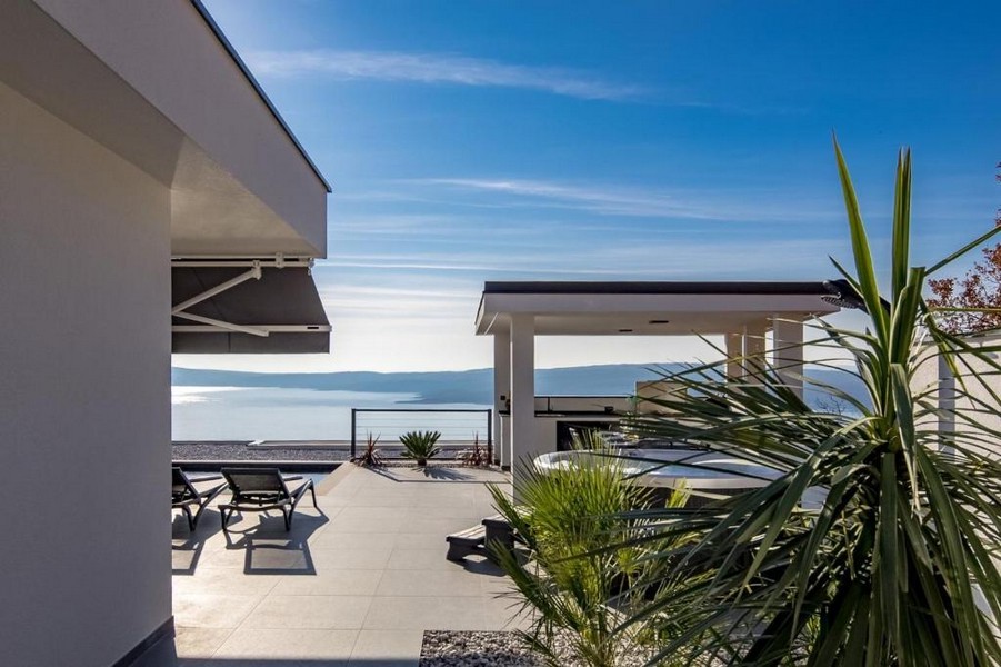 Terrasse avec transats et pavillon au-dessus de la plage de galets