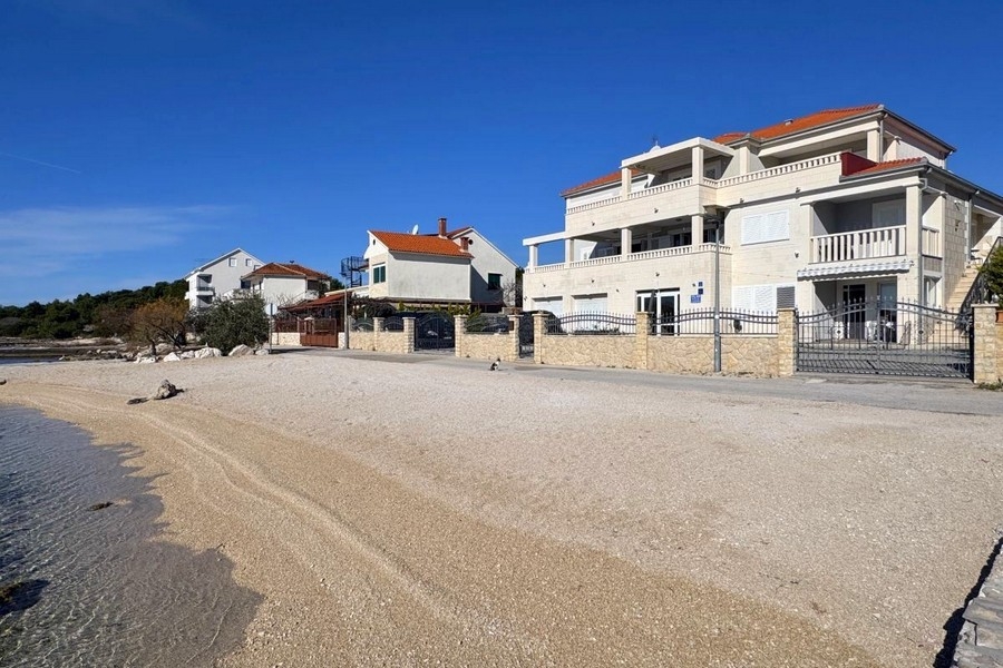 Maison avec balcons sur la plage de galets sous un ciel bleu