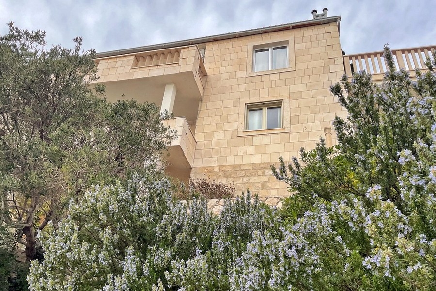 Façade de la maison en pierre naturelle avec balcon et jardin