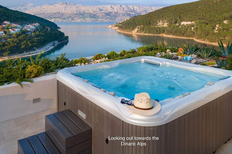 Bain à remous avec chapeau de paille et vue sur la baie jusqu'aux montagnes