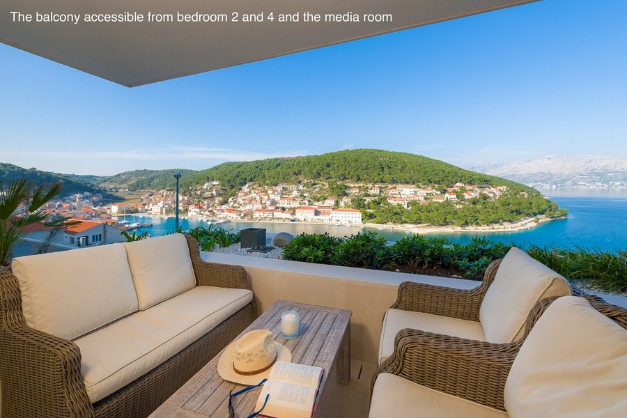 Balcon couvert avec coin salon et vue sur la baie et le village