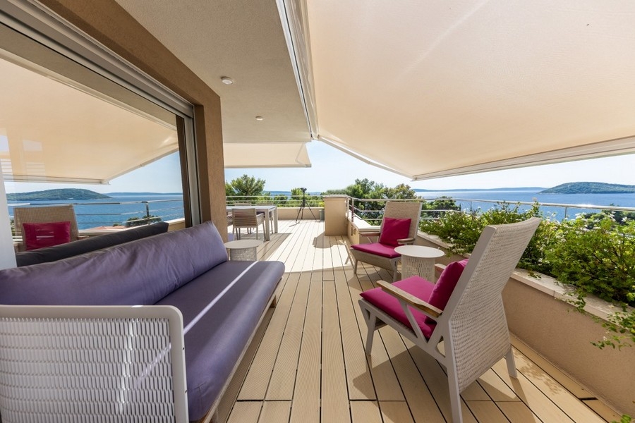 Terrasse avec store et fauteuils roses au-dessus de la baie
