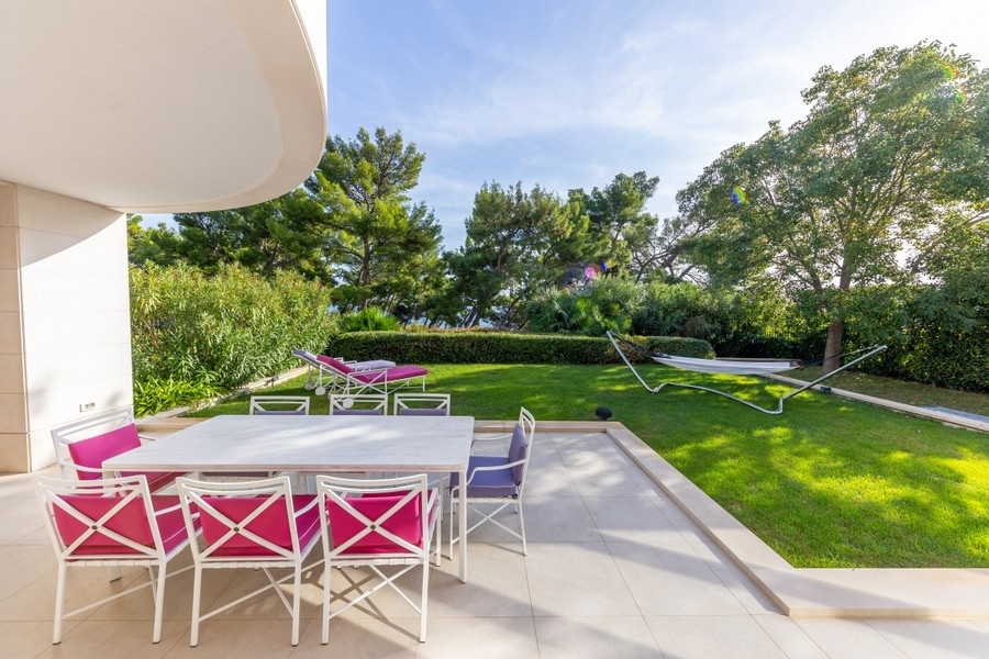 Terrasse avec table à manger et jardin soigné de la villa
