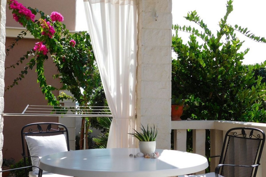 Terrasse couverte avec salon de jardin et bougainvillée