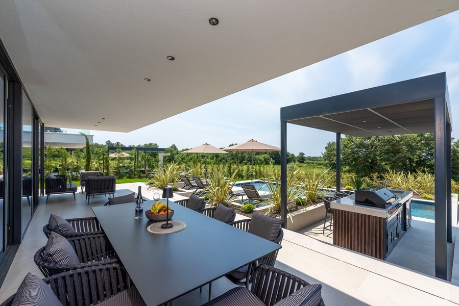 Terrasse couverte avec coin repas et cuisine extérieure au bord de la piscine