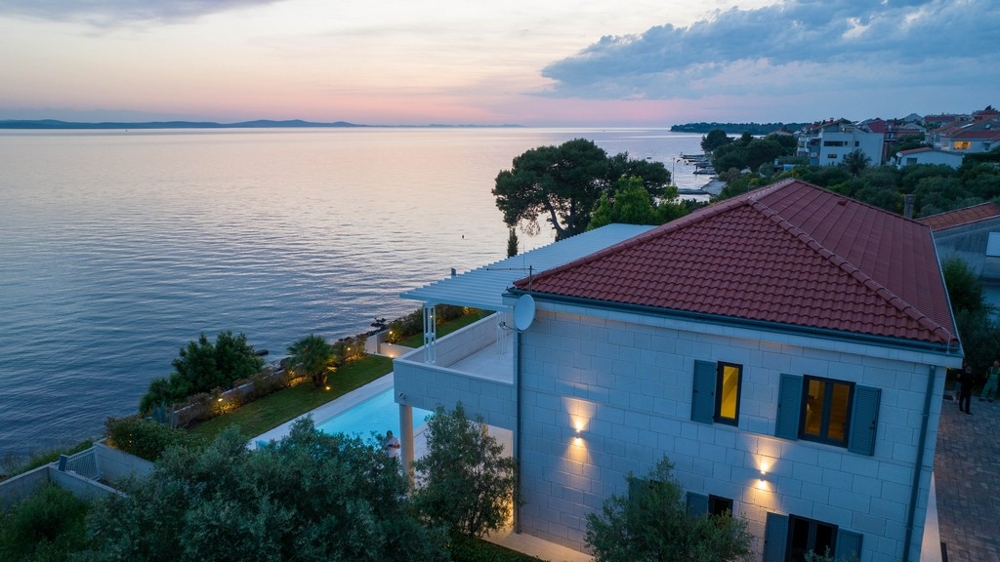 Maison éclairée à toit de tuiles et piscine au bord de l'eau