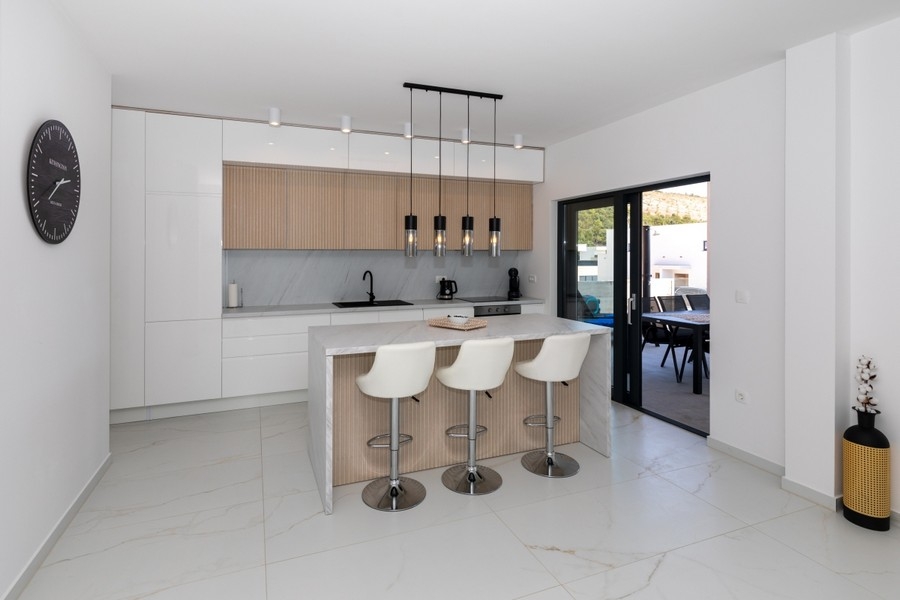 Cuisine contemporaine avec îlot de cuisson et accès à la terrasse