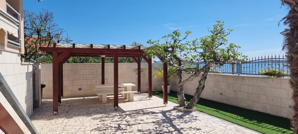 Espace extérieur entretenu avec coin salon sous la pergola et plantations méditerranéennes