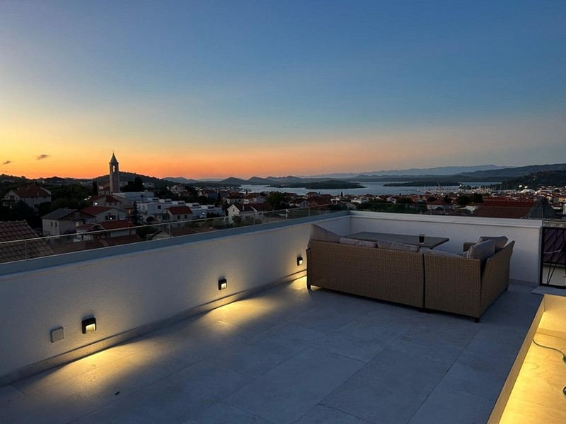 Toit-terrasse avec lounge et vue sur le clocher au coucher du soleil
