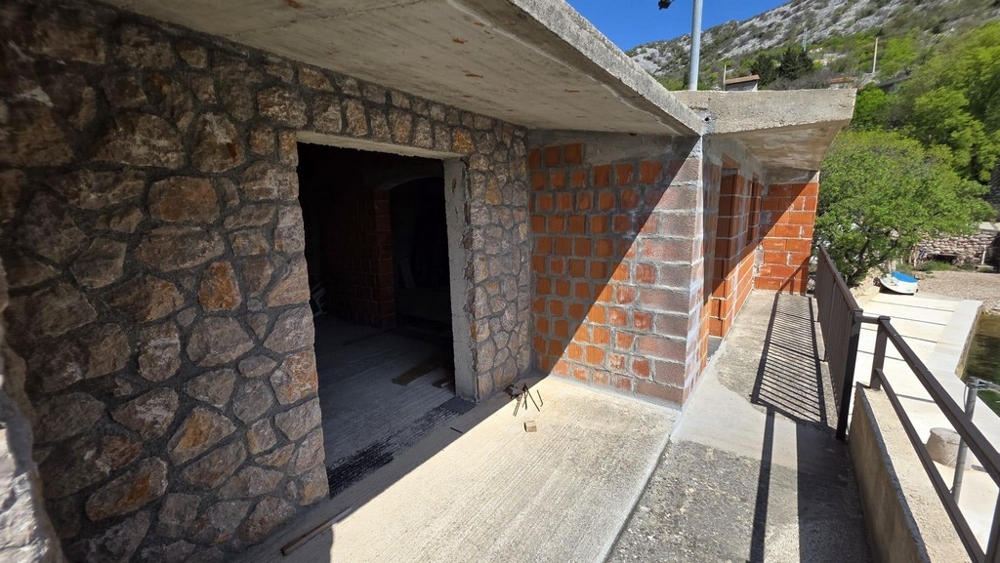 Espace extérieur avec mur en pierre naturelle et terrasse couverte