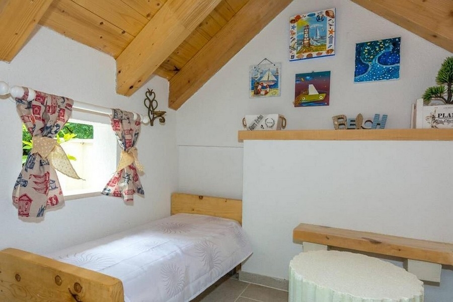 Espace nuit sous les combles avec poutres en bois et atmosphère chaleureuse
