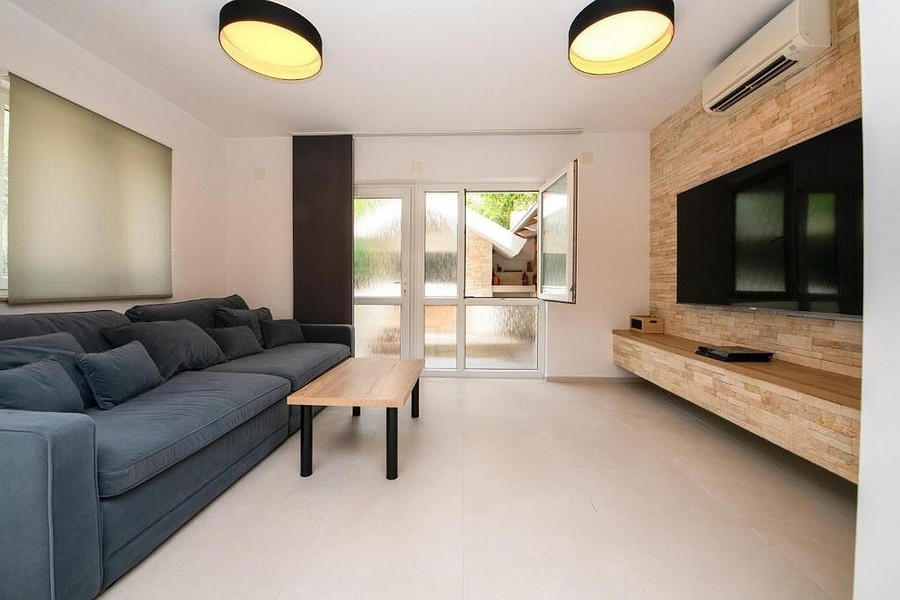 Salon moderne avec canapé, meuble TV et accès à la terrasse