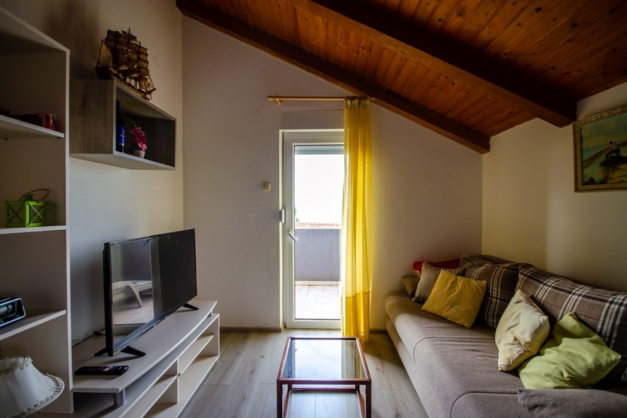 Séjour sous les combles avec canapé et accès au balcon