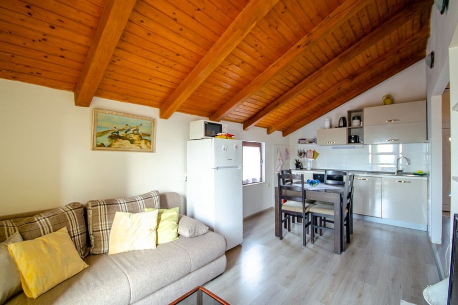 Séjour et coin repas avec cuisine ouverte et plafond à poutres en bois