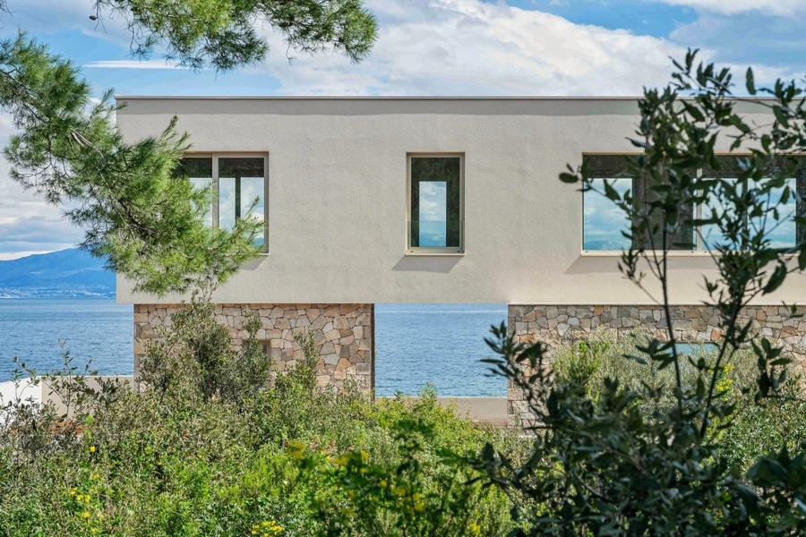Maison à soubassement en pierre naturelle parmi les pins au-dessus de l'eau