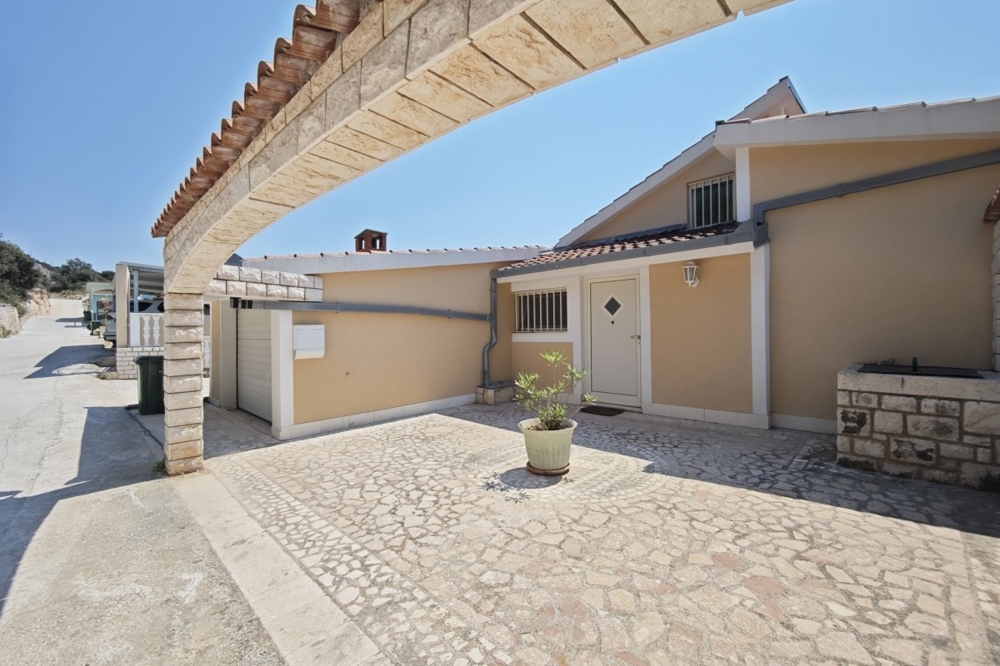 Façade de la maison avec garage et cour pavée