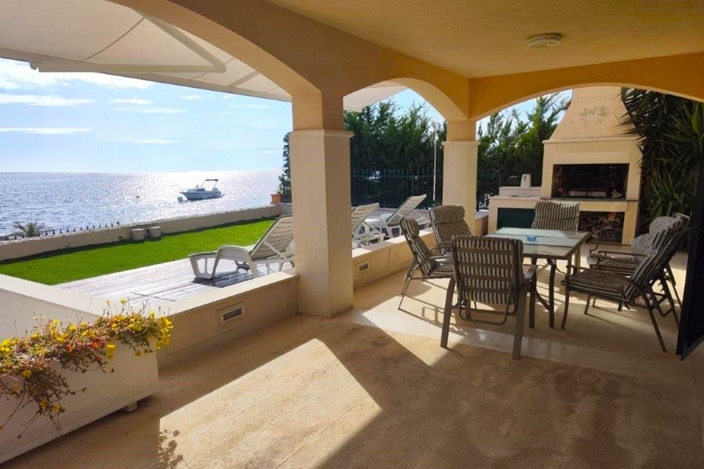 Terrasse couverte avec cheminée et vue sur la pelouse jusqu'à la mer