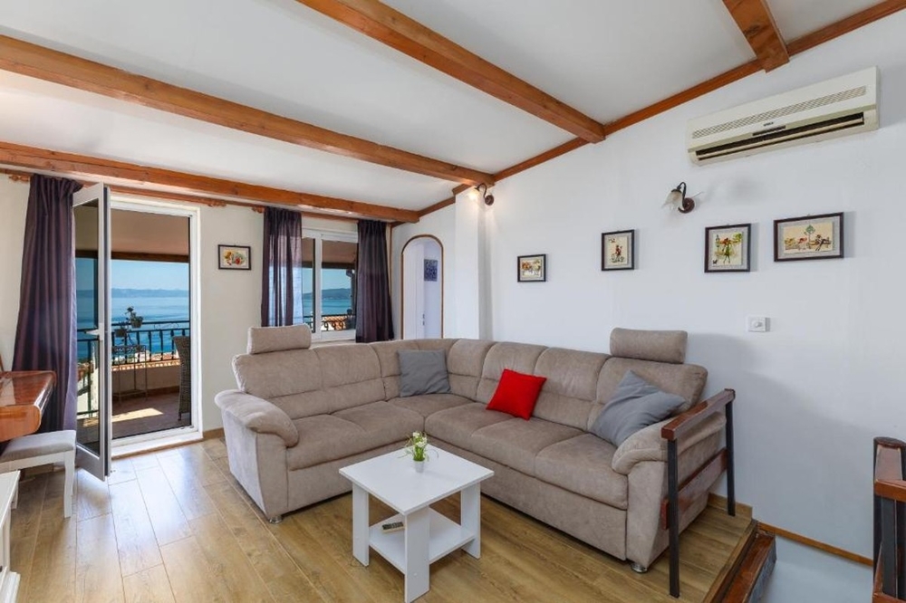 Salon avec canapé d'angle et accès au balcon avec vue mer