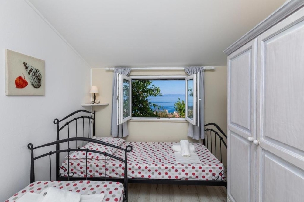 Chambre avec lits simples et vue mer par la fenêtre