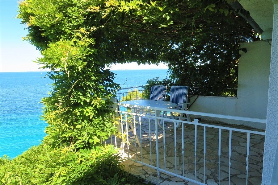 Terrasse sous un feuillage avec vue sur l'eau turquoise