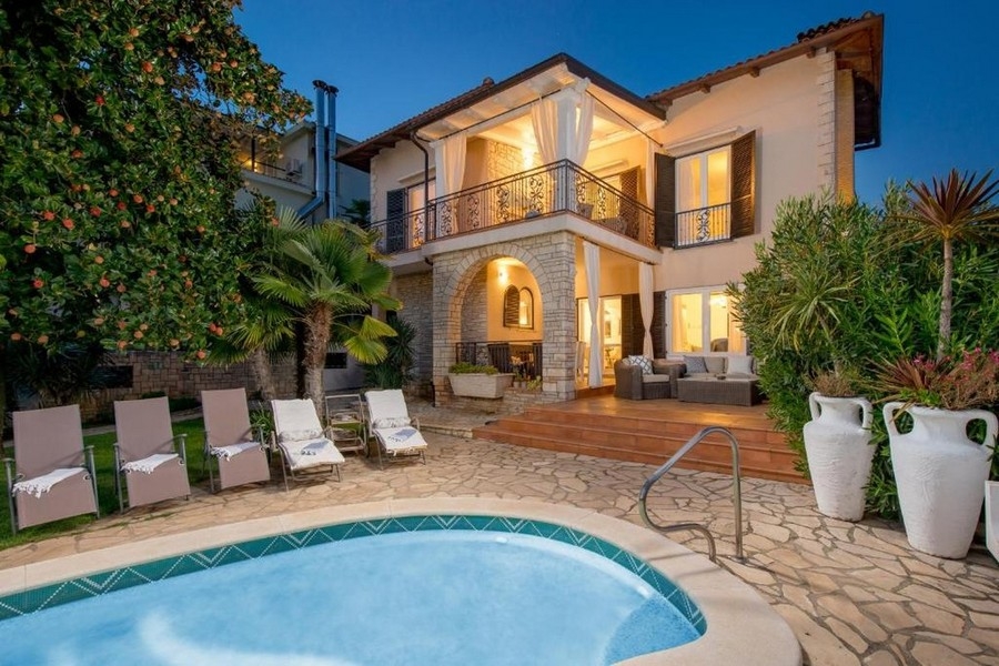 Villa éclairée avec palmiers et piscine au crépuscule