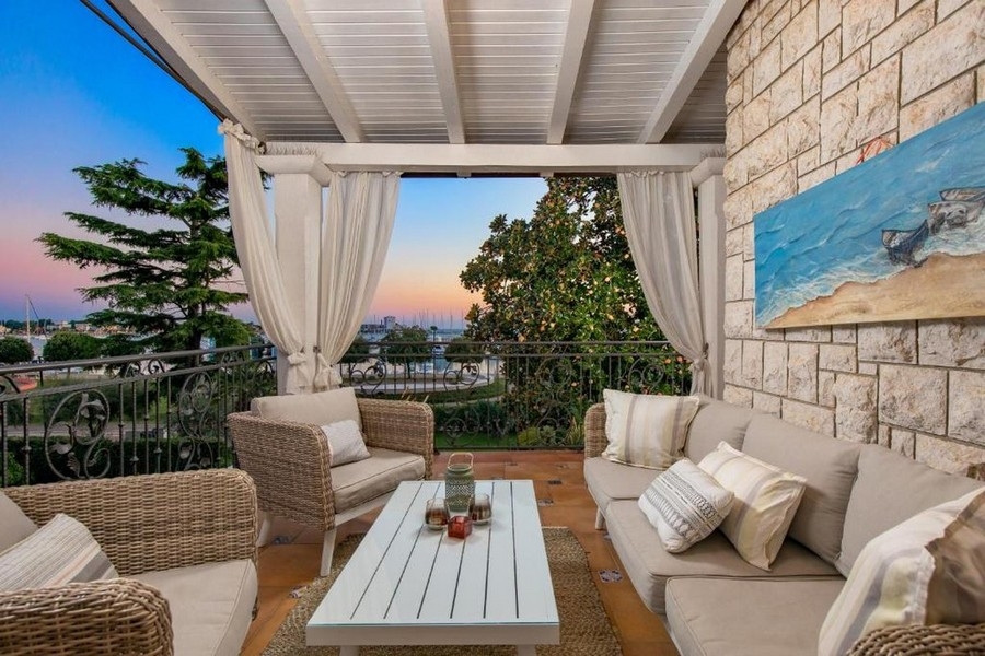 Balcon avec mobilier lounge et vue mer au coucher du soleil