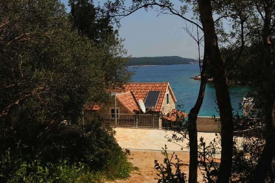 Maison en pierre avec vue mer entre les arbres