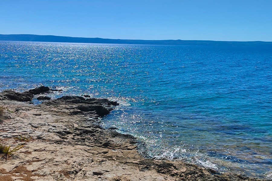 Côte rocheuse avec eau scintillante et île à l'horizon