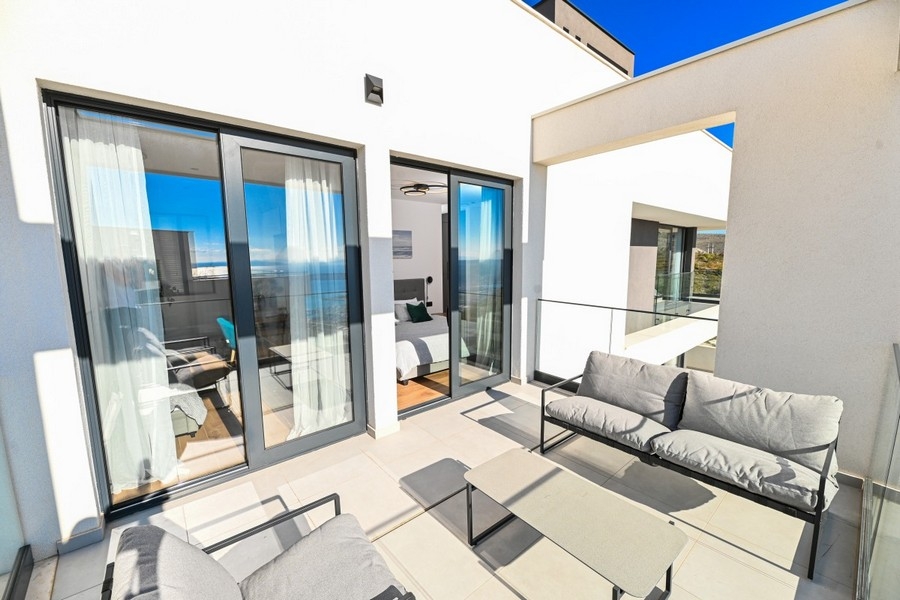 Spacieuse terrasse avec coin salon et façade vitrée