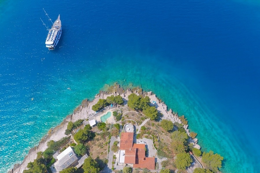 Vue aérienne de la langue de terre avec maison, piscine et bateau d'excursion